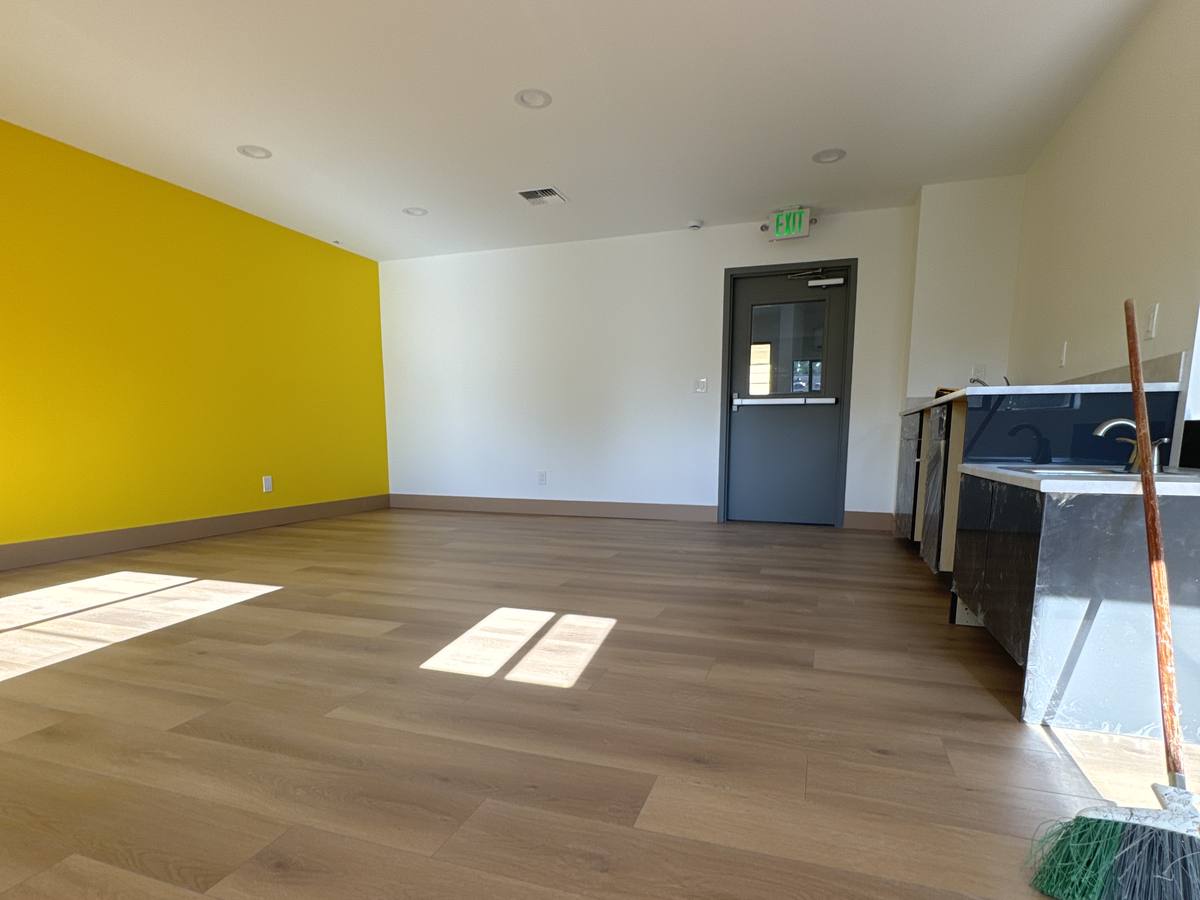 Finished classroom with yellow accent wall, wood-look flooring and daylight from the windows